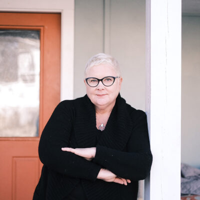 Human Rights Commission chair Mary Bauer stands in front of a door.