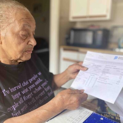 Carolyn Johnson stands in her kitchen showing her Dominion energy bill