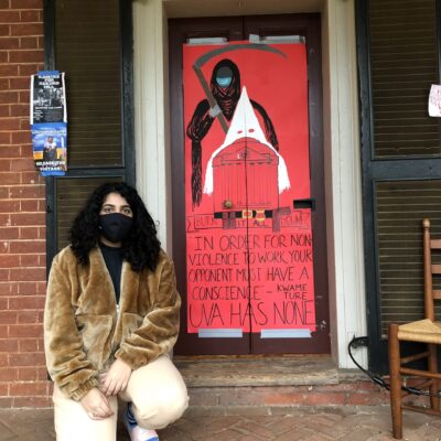 Hira Azher kneels on the ground in front of her Lawn room sign