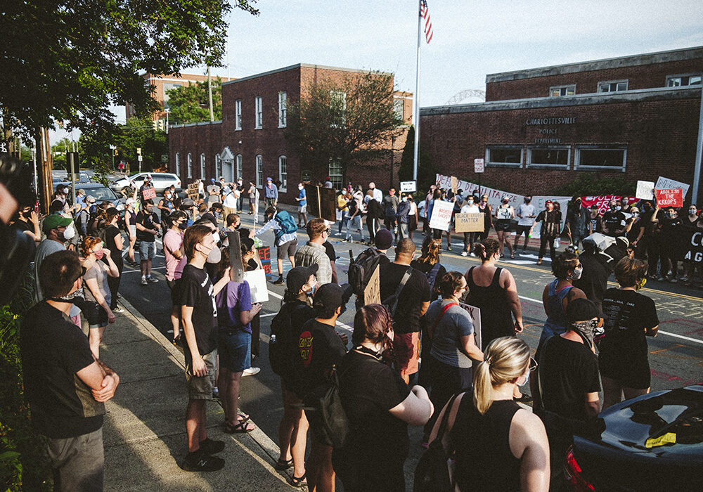 Dozens of local residents protesting and holding signs across the stress from the Charlottesville Police Department