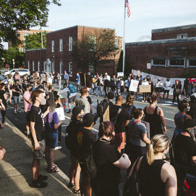 Dozens of local residents protesting and holding signs across the stress from the Charlottesville Police Department