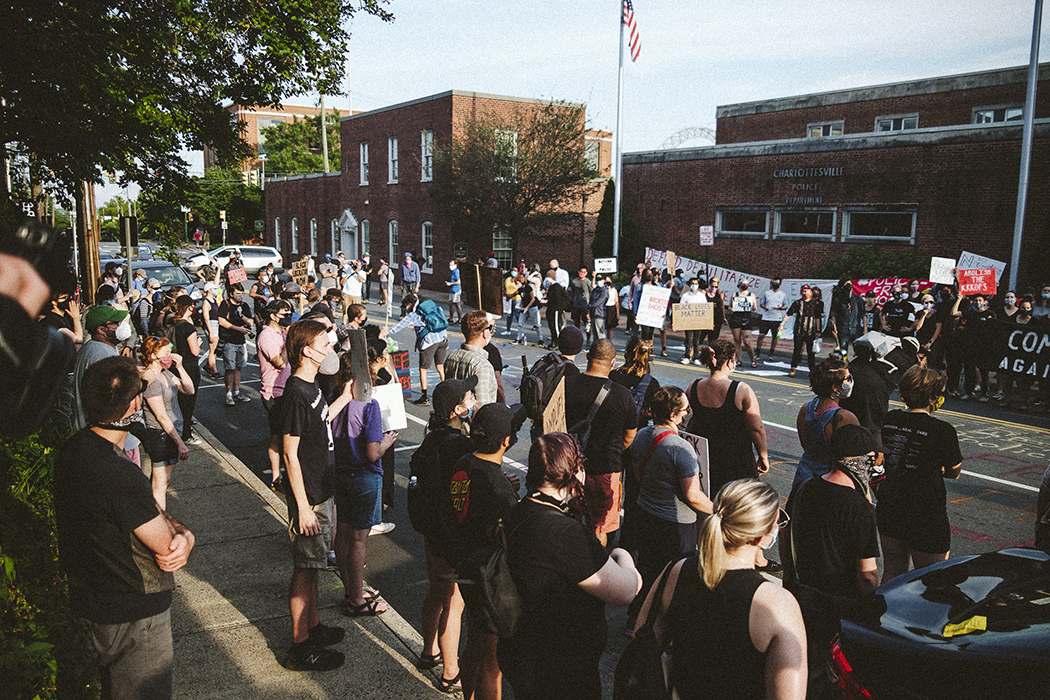 Dozens of local residents protesting and holding signs across the stress from the Charlottesville Police Department