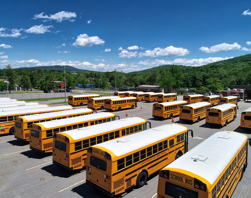 Fleet of yellow school buses in a parking lot under a sunny blue sky