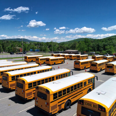 Fleet of yellow school buses in a parking lot under a sunny blue sky