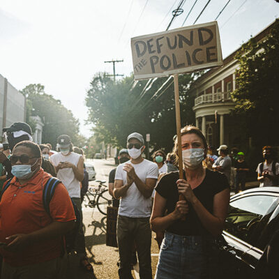 Group of protestors in downtown Charlottesville, one person holds a Defund the Police sign